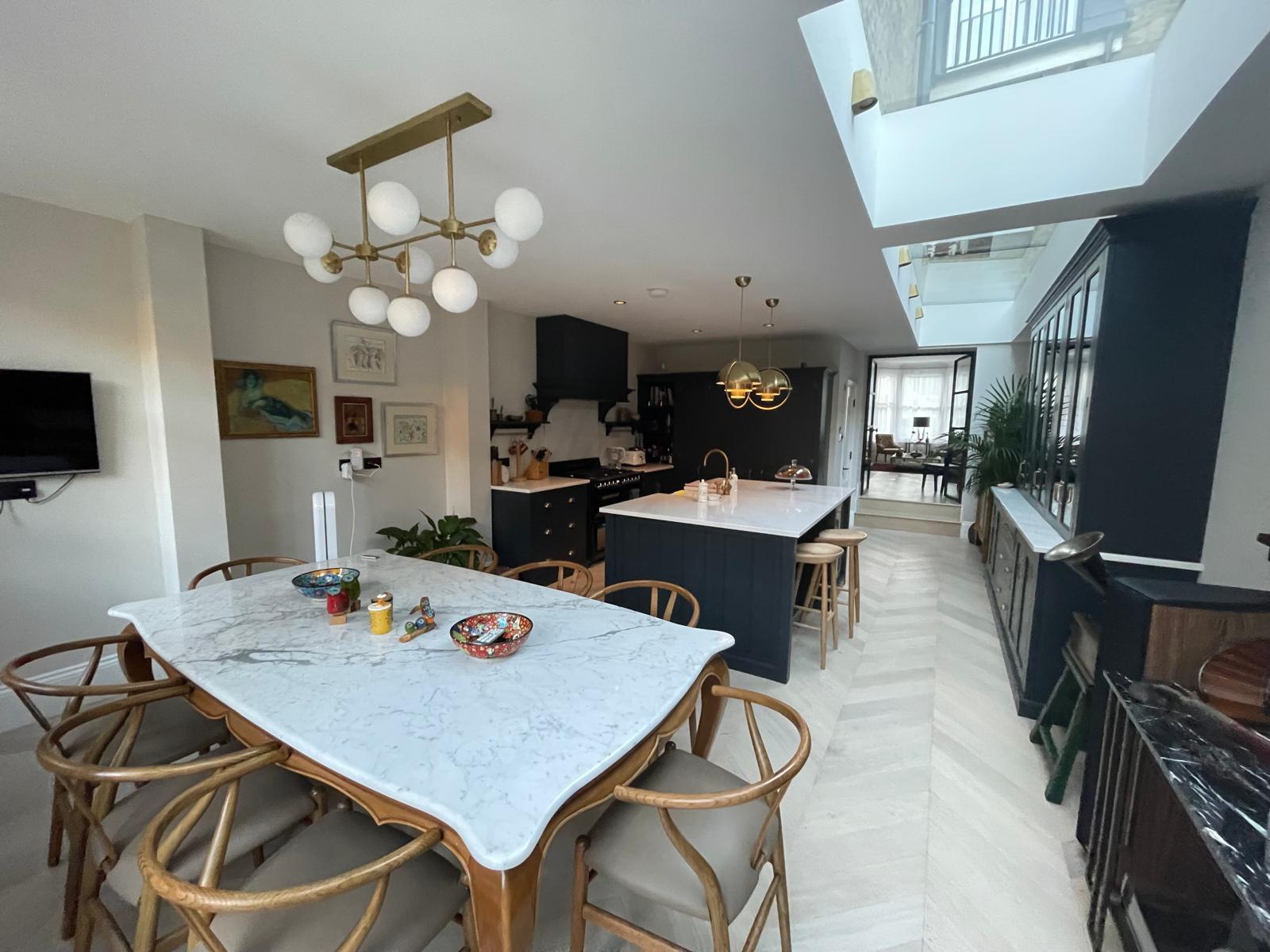 Completed New Level open-plan kitchen with dark painted cabinetry and marble island