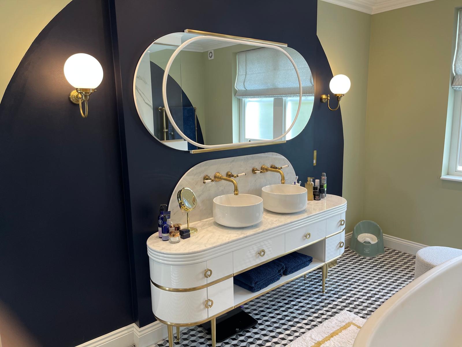 Curved bathroom vanity with brass fittings and mirrors